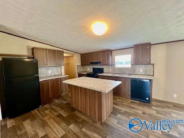 kitchen with a textured ceiling, black appliances, dark wood-type flooring, and a kitchen island