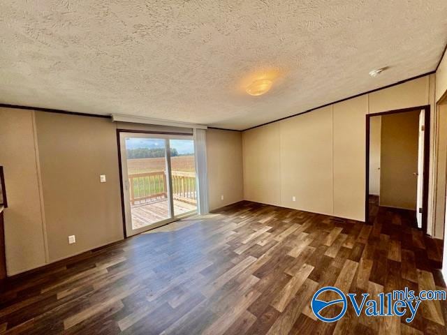 empty room with a textured ceiling and dark hardwood / wood-style flooring