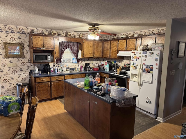kitchen featuring range with electric cooktop, a textured ceiling, white fridge with ice dispenser, a center island, and stainless steel microwave