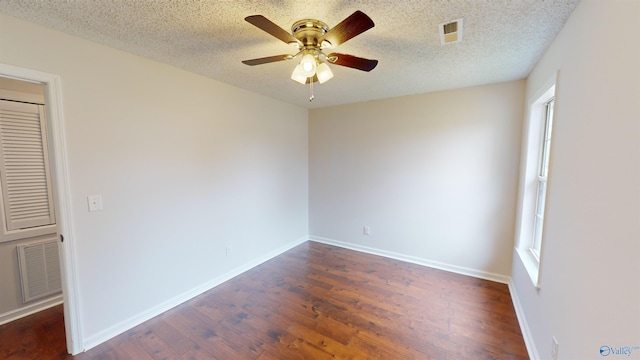 spare room featuring ceiling fan, a healthy amount of sunlight, a textured ceiling, and dark hardwood / wood-style flooring