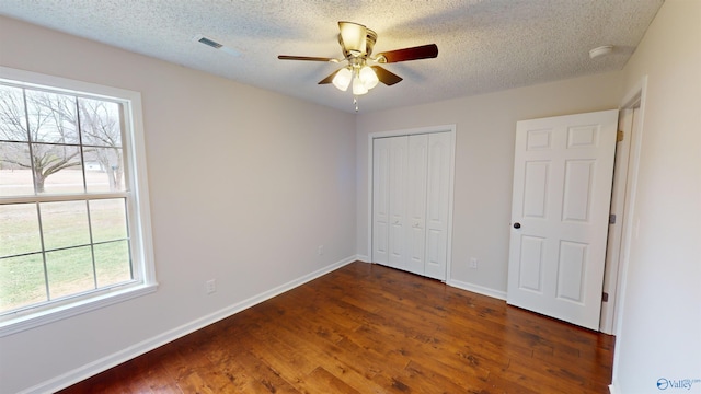 unfurnished bedroom featuring ceiling fan, a textured ceiling, dark hardwood / wood-style flooring, and a closet