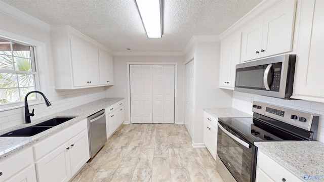 kitchen with stainless steel appliances, white cabinetry, and sink