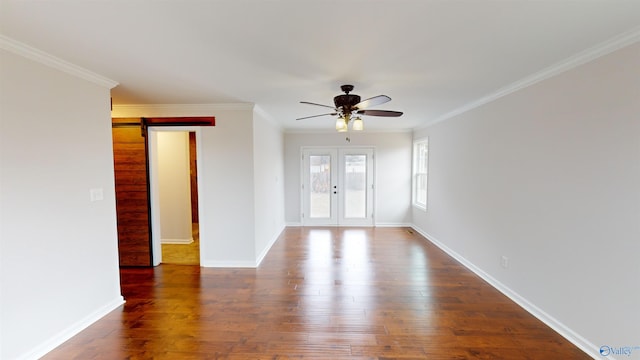 spare room featuring french doors, dark wood-type flooring, crown molding, ceiling fan, and a barn door