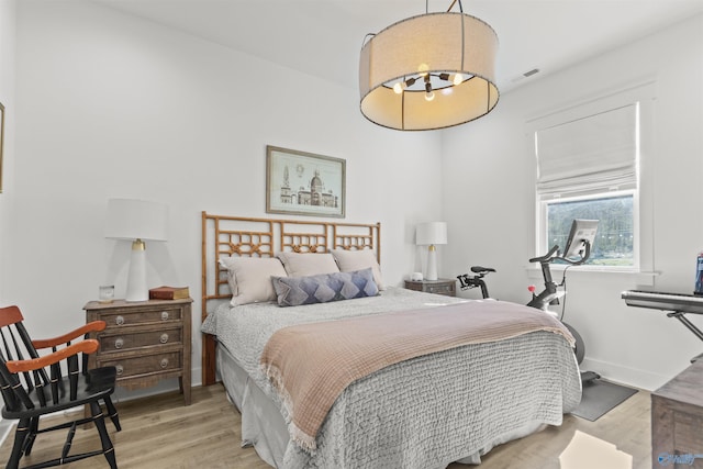 bedroom featuring light wood finished floors, visible vents, and baseboards