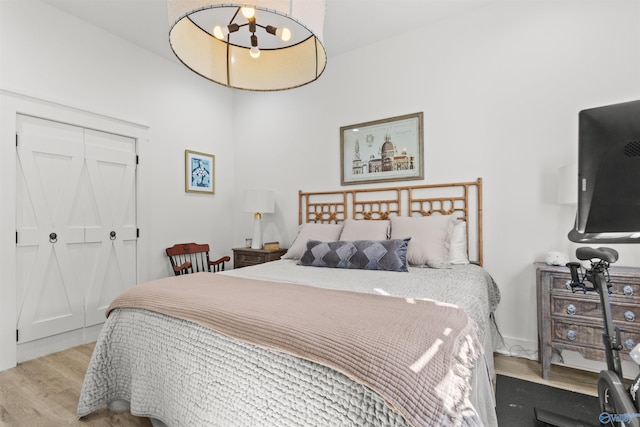 bedroom with light wood-style floors, a closet, and a chandelier