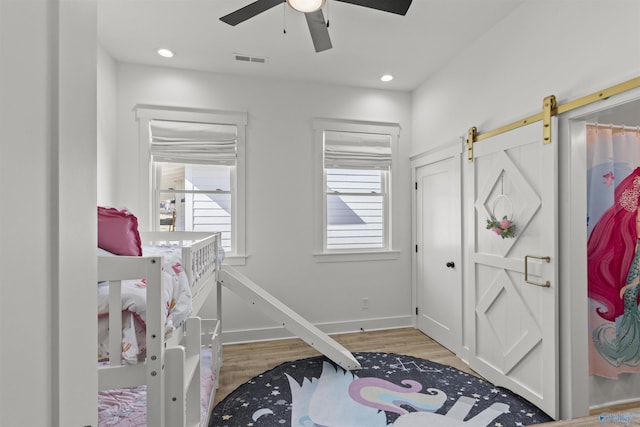 bedroom featuring a barn door, recessed lighting, visible vents, baseboards, and light wood finished floors