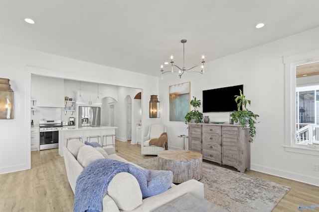 living area with light wood-style floors, baseboards, arched walkways, and recessed lighting