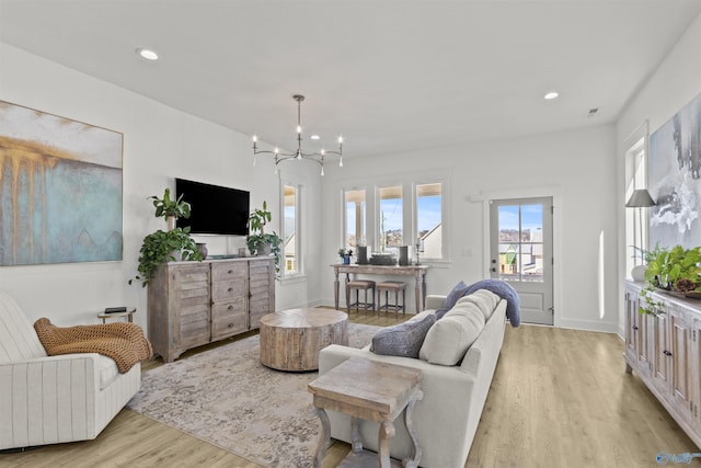 living room featuring light wood-style floors, recessed lighting, a notable chandelier, and baseboards