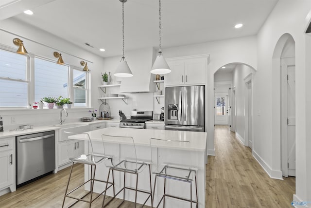 kitchen featuring appliances with stainless steel finishes, light countertops, a kitchen island, and open shelves