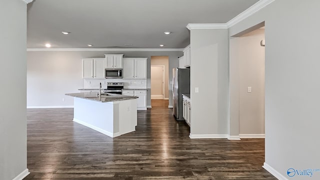 kitchen featuring dark stone counters, stainless steel appliances, a kitchen island with sink, dark hardwood / wood-style floors, and white cabinetry