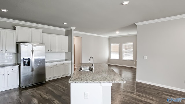 kitchen featuring stainless steel refrigerator with ice dispenser, tasteful backsplash, sink, a center island with sink, and white cabinetry