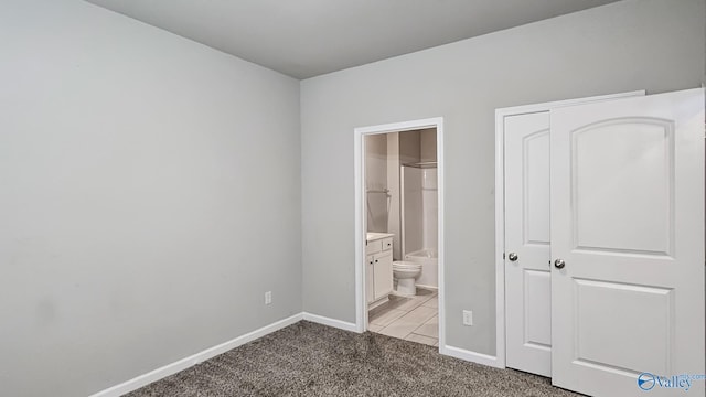 unfurnished bedroom featuring light carpet and ensuite bath