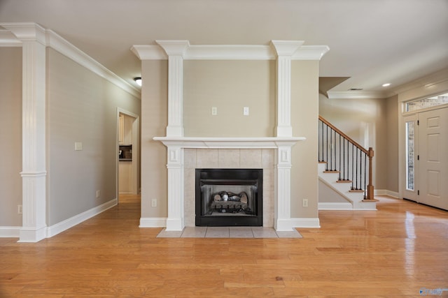 22222 Merlot Dr, Athens, AL 35613 - unfurnished living room featuring stairway, a tile fireplace, light wood finished floors, and ornamental molding