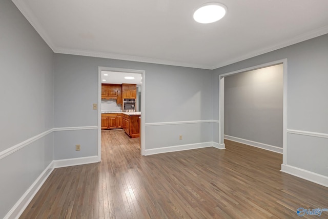 empty room featuring dark wood finished floors, baseboards, and ornamental molding