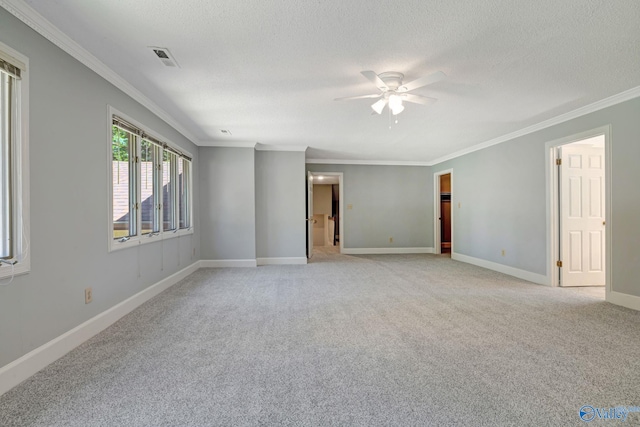 unfurnished room with visible vents, baseboards, light colored carpet, ornamental molding, and a textured ceiling