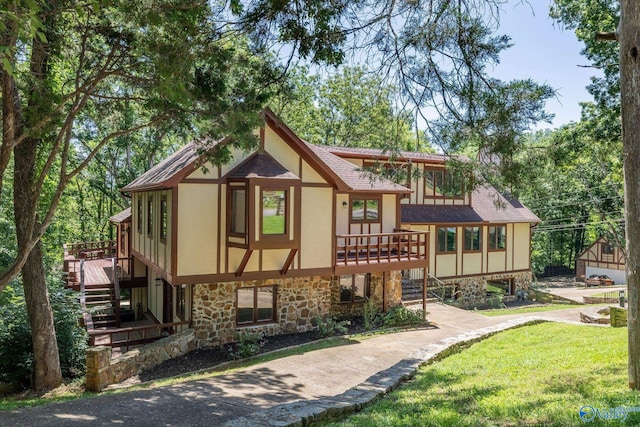 view of front of property with a shingled roof, stairway, a front yard, stucco siding, and stone siding