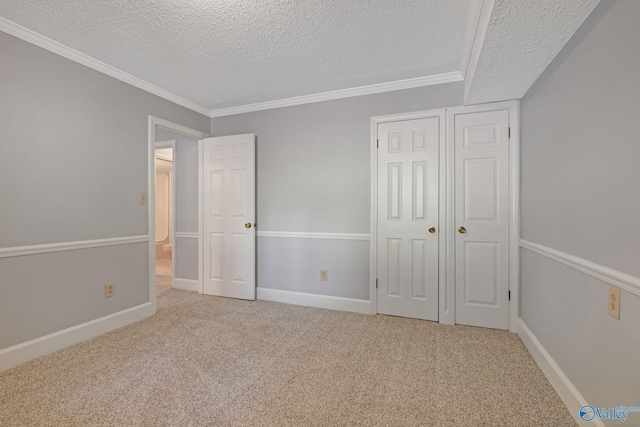 unfurnished bedroom featuring ornamental molding, a textured ceiling, baseboards, and carpet floors