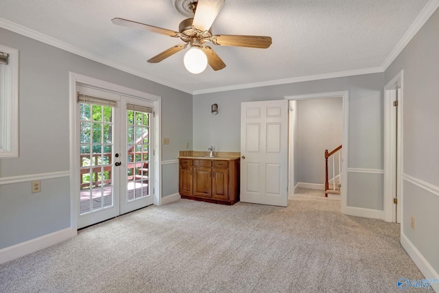 empty room featuring french doors, light colored carpet, and ornamental molding