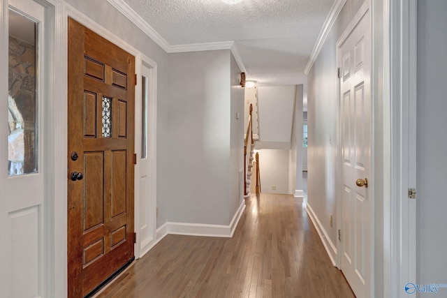 foyer featuring crown molding, wood finished floors, baseboards, and a textured ceiling