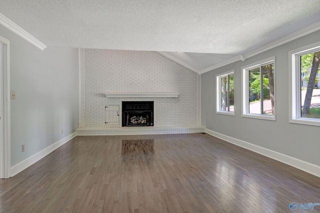 unfurnished living room with a textured ceiling, wood finished floors, crown molding, a brick fireplace, and vaulted ceiling