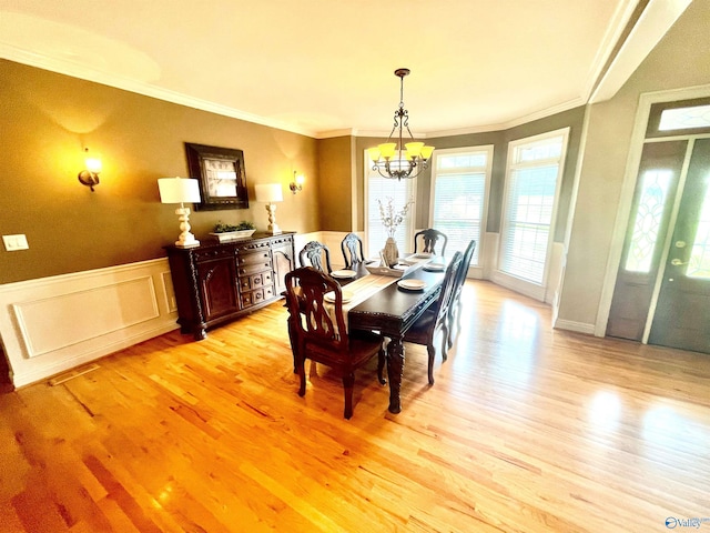 dining area featuring light wood-type flooring, a chandelier, and crown molding