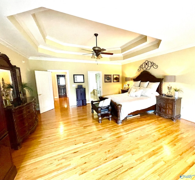 bedroom featuring ceiling fan, ornamental molding, a tray ceiling, and hardwood / wood-style floors