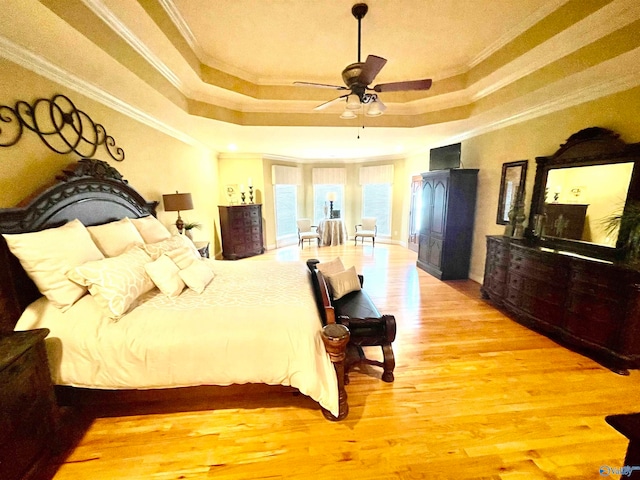 bedroom with a raised ceiling, ornamental molding, hardwood / wood-style floors, and ceiling fan