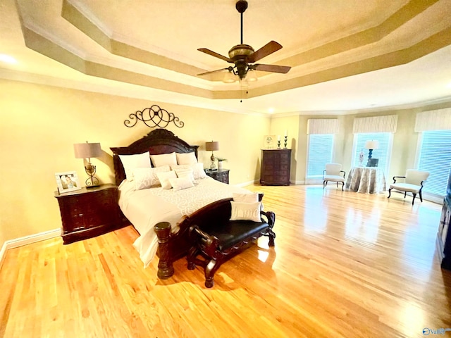 bedroom with a raised ceiling, light hardwood / wood-style floors, crown molding, and ceiling fan