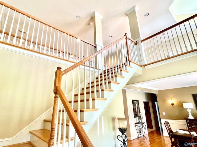 staircase featuring a towering ceiling and hardwood / wood-style floors