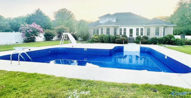 view of swimming pool featuring a diving board, a water slide, and a yard