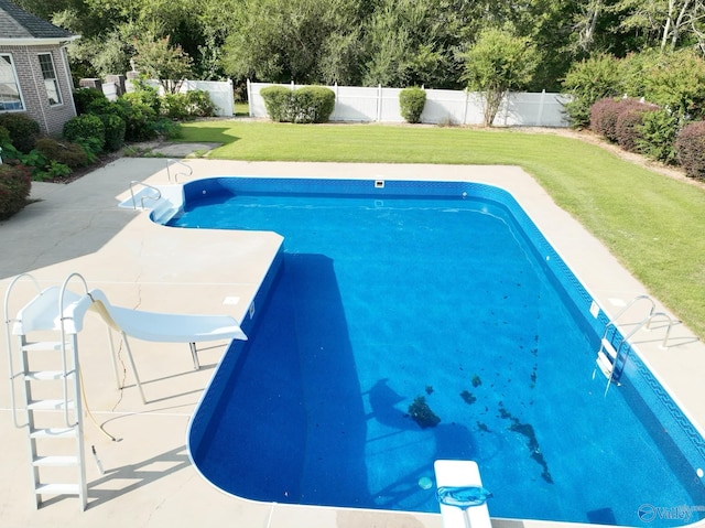 view of swimming pool with a diving board, a water slide, and a yard