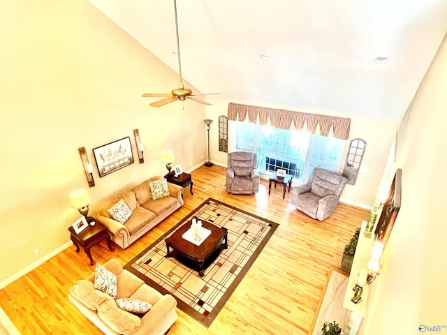 living room with light wood-type flooring, ceiling fan, and high vaulted ceiling