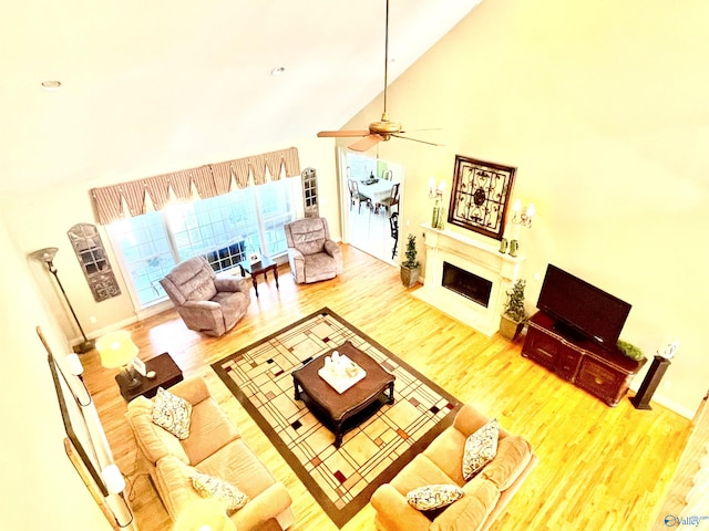 living room with light hardwood / wood-style flooring, ceiling fan, and high vaulted ceiling