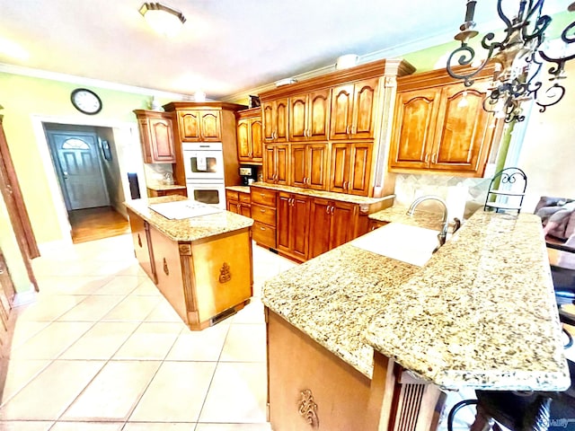 kitchen featuring crown molding, white double oven, and light stone counters