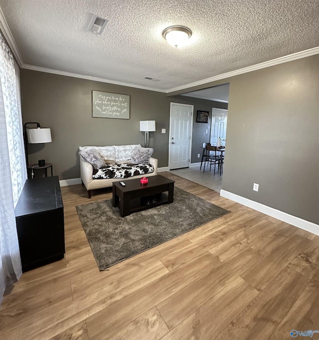 26 Prospect St, Town Creek, AL 35672 - living room featuring a textured ceiling, light wood finished floors, baseboards, ornamental molding, and visible vents