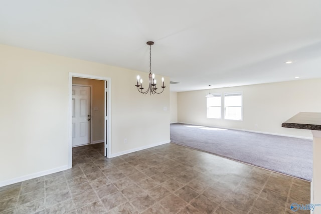 carpeted empty room featuring an inviting chandelier