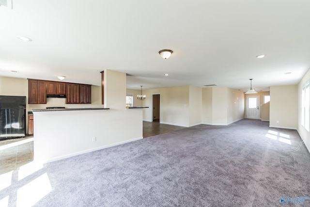 unfurnished living room with carpet and a notable chandelier