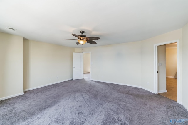 spare room with ceiling fan and dark colored carpet