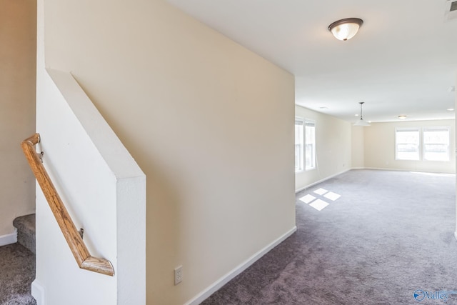 corridor featuring a healthy amount of sunlight and dark colored carpet