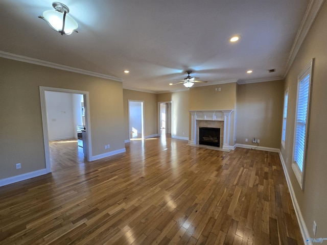 unfurnished living room featuring a premium fireplace, crown molding, dark hardwood / wood-style flooring, and a healthy amount of sunlight