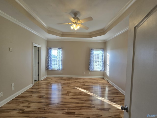 empty room featuring wood-type flooring, ornamental molding, and a tray ceiling