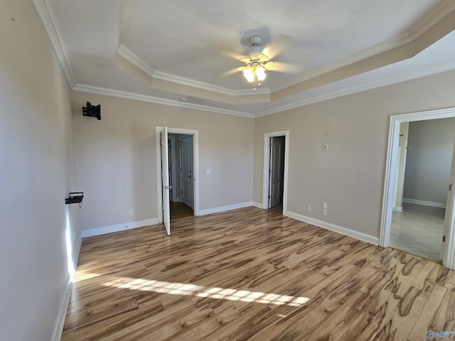 unfurnished bedroom featuring crown molding, ceiling fan, a raised ceiling, and light hardwood / wood-style flooring