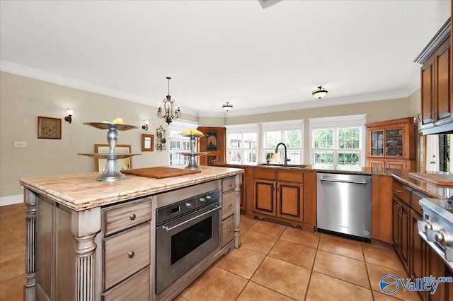 83 James Rd, Hartselle, AL 35640 - kitchen with stainless steel appliances, crown molding, light tile patterned floors, brown cabinets, and hanging light fixtures
