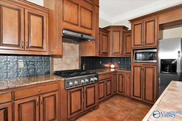 83 James Rd, Hartselle, AL 35640 - kitchen featuring stainless steel appliances, under cabinet range hood, brown cabinetry, tile patterned flooring, and ornamental molding