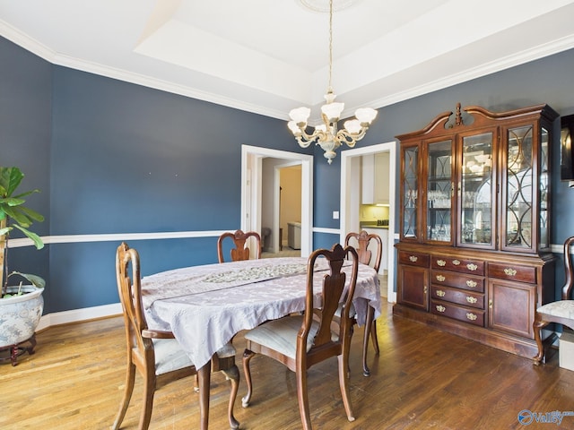 dining room with baseboards, a tray ceiling, a notable chandelier, and wood finished floors