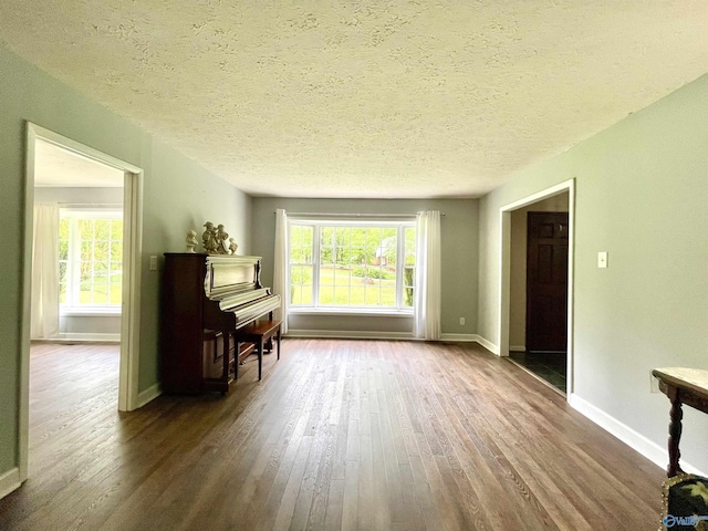 living area featuring a textured ceiling, wood finished floors, and baseboards