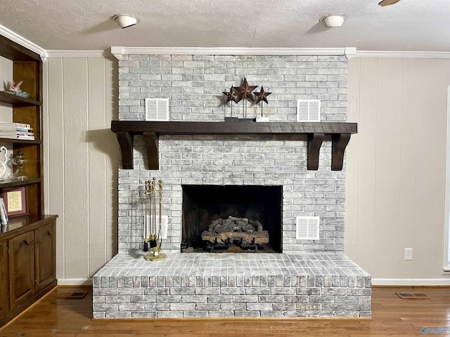 details featuring wood finished floors, a textured ceiling, visible vents, crown molding, and baseboards