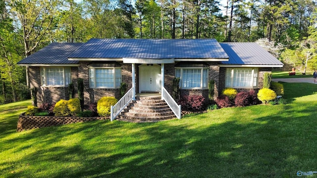 single story home featuring metal roof, brick siding, and a front yard