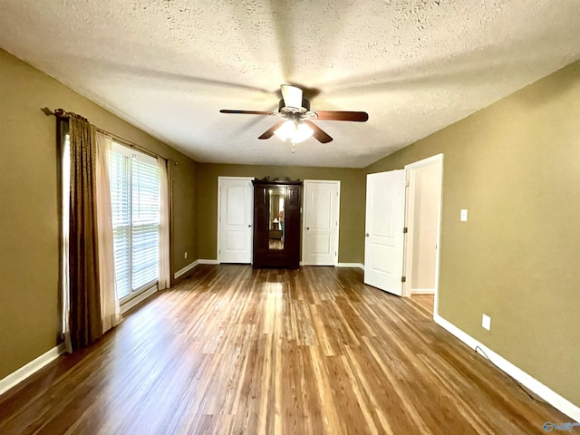 unfurnished bedroom featuring a textured ceiling, wood finished floors, and baseboards