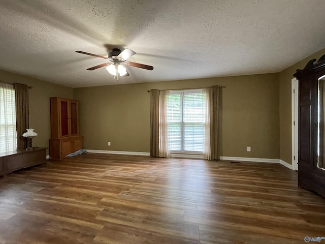 unfurnished room with baseboards, ceiling fan, a textured ceiling, and wood finished floors